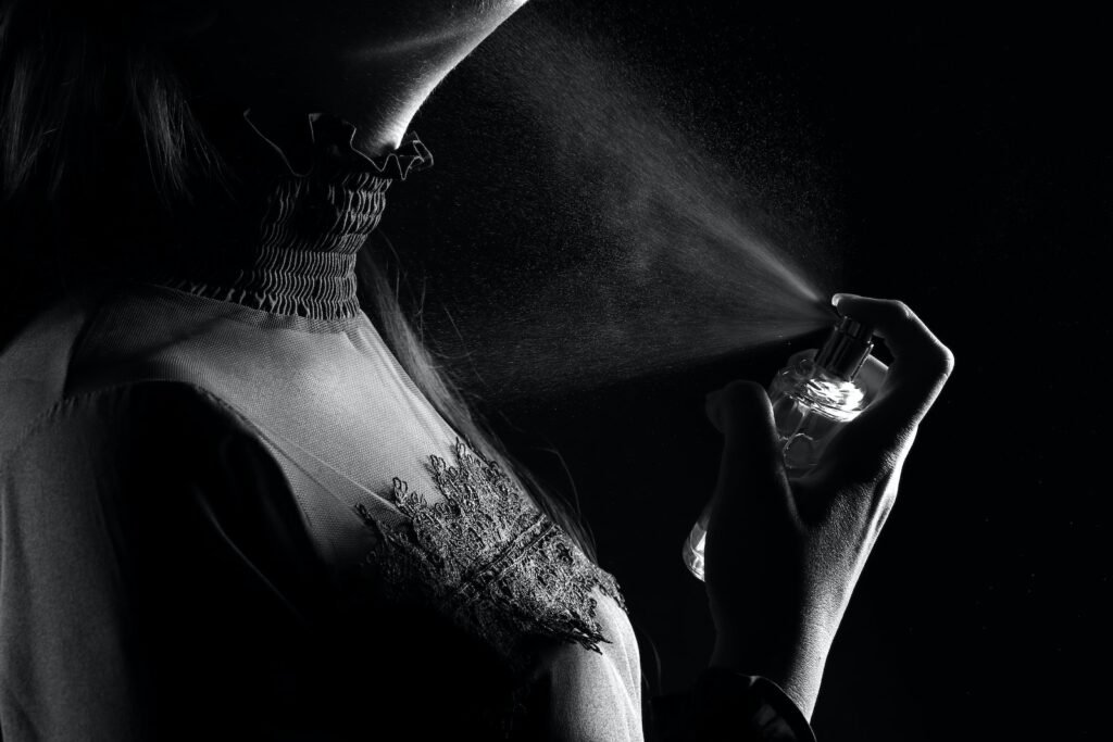 Grayscale Photo of Person Spraying Perfume