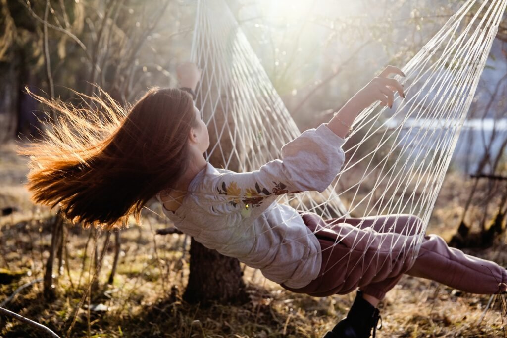 Girl with Long Red Hair Sitting in Hammock and Swinging