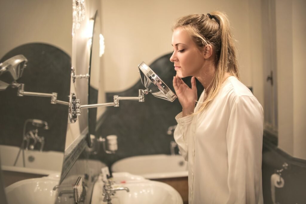 Upset woman examining skin in small mirror