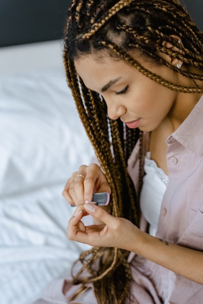 A Braided Hair Woman Filing Her Fingernails