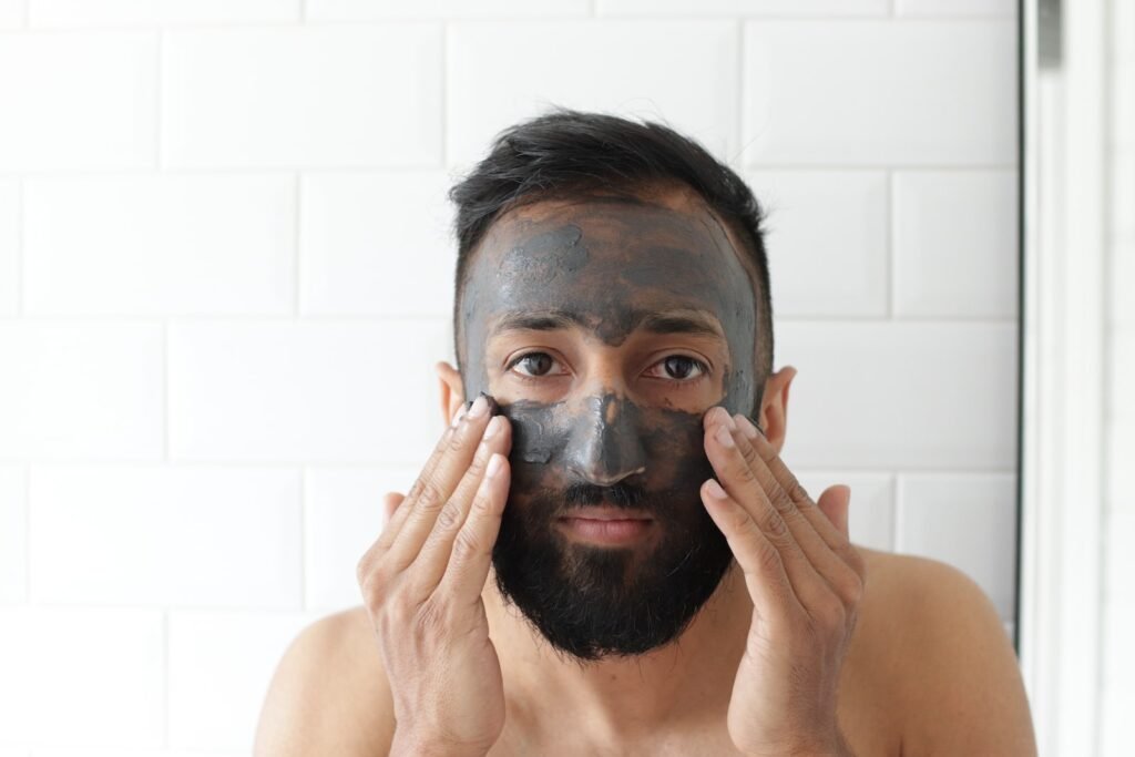 Indian man applying charcoal face mask