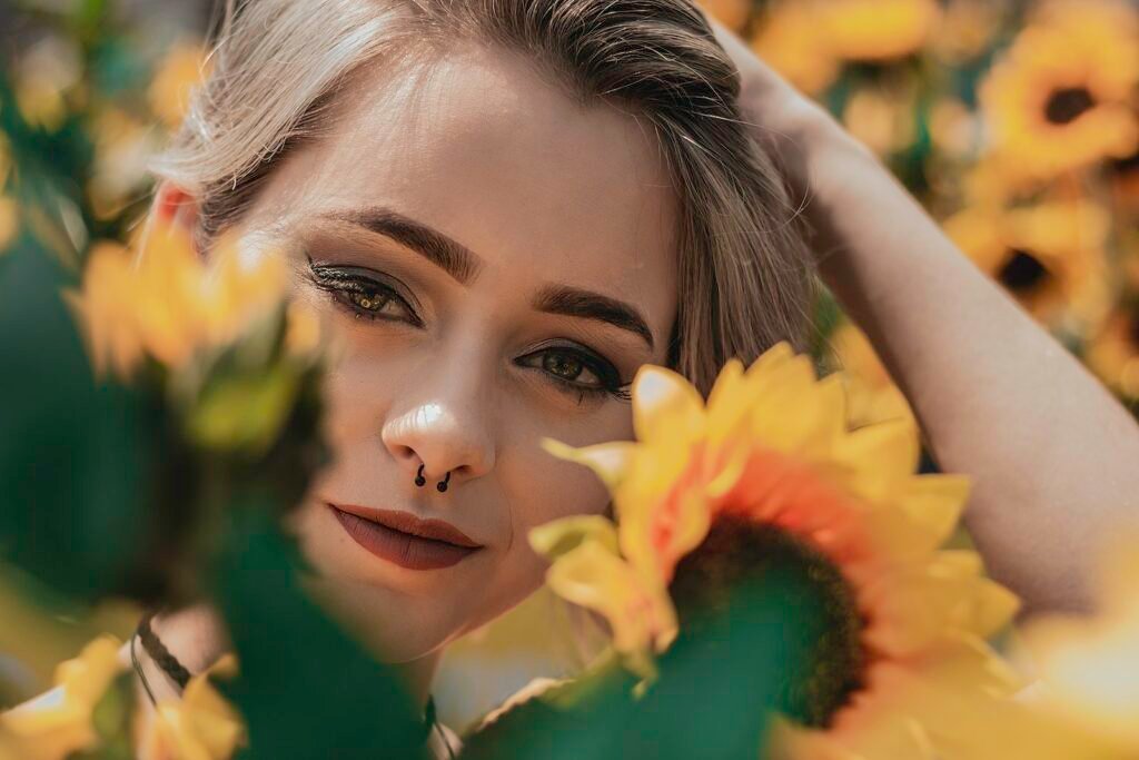 Close-up Photo of Smiling Woman Posing by Yellow Sunflowers