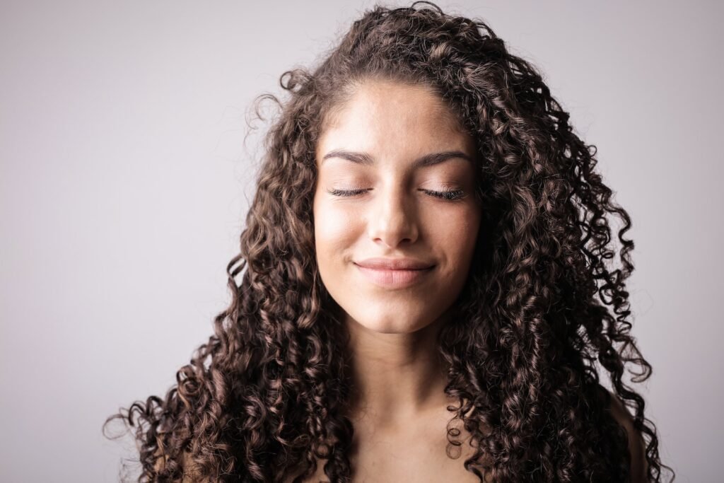 Smiling Woman with Brown Curly Hair with Her Eyes Closed