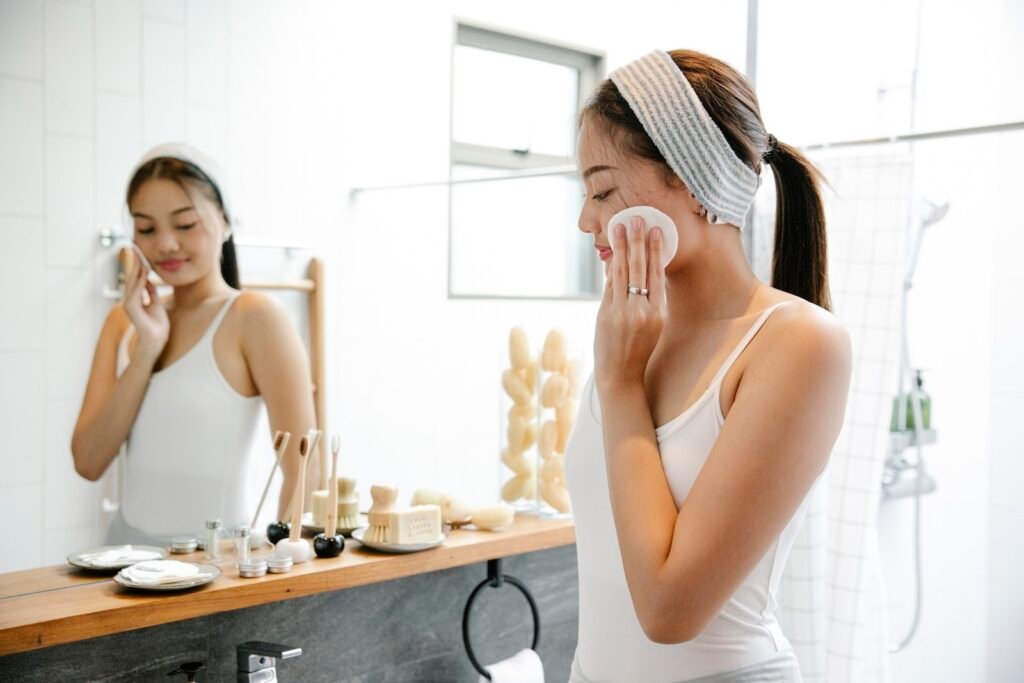 woman cleaning face with cotton pad